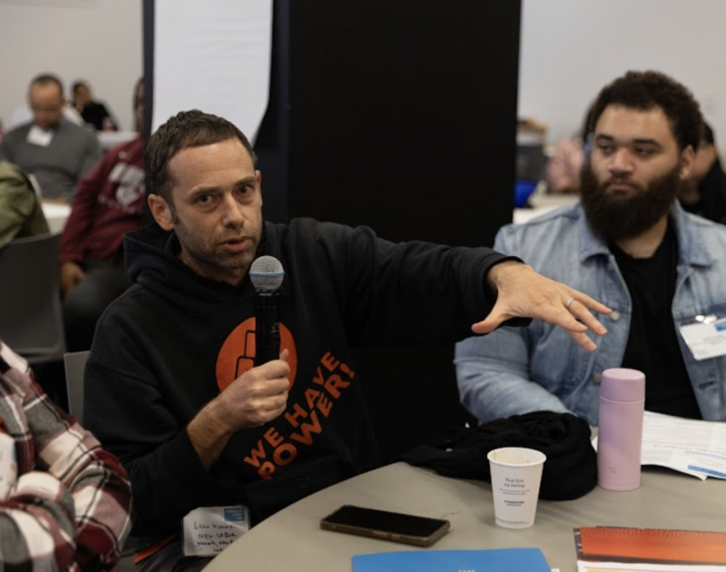 Man on a microphone speaking to a group